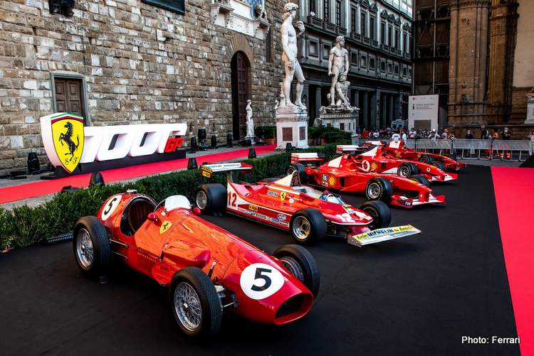 Multiple F1 Ferrari race cars side by side on a red carpet. There is a “1000GP” sign behind the cars